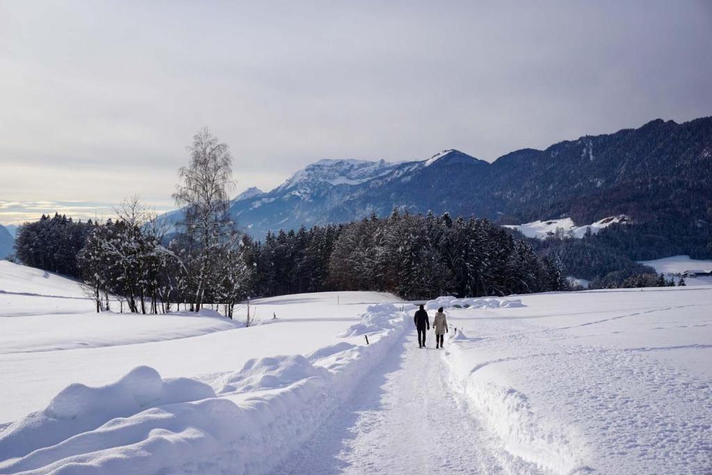two people walking down a snow covered road at Kathrins Ferienwohnung in Breitenbach am Inn