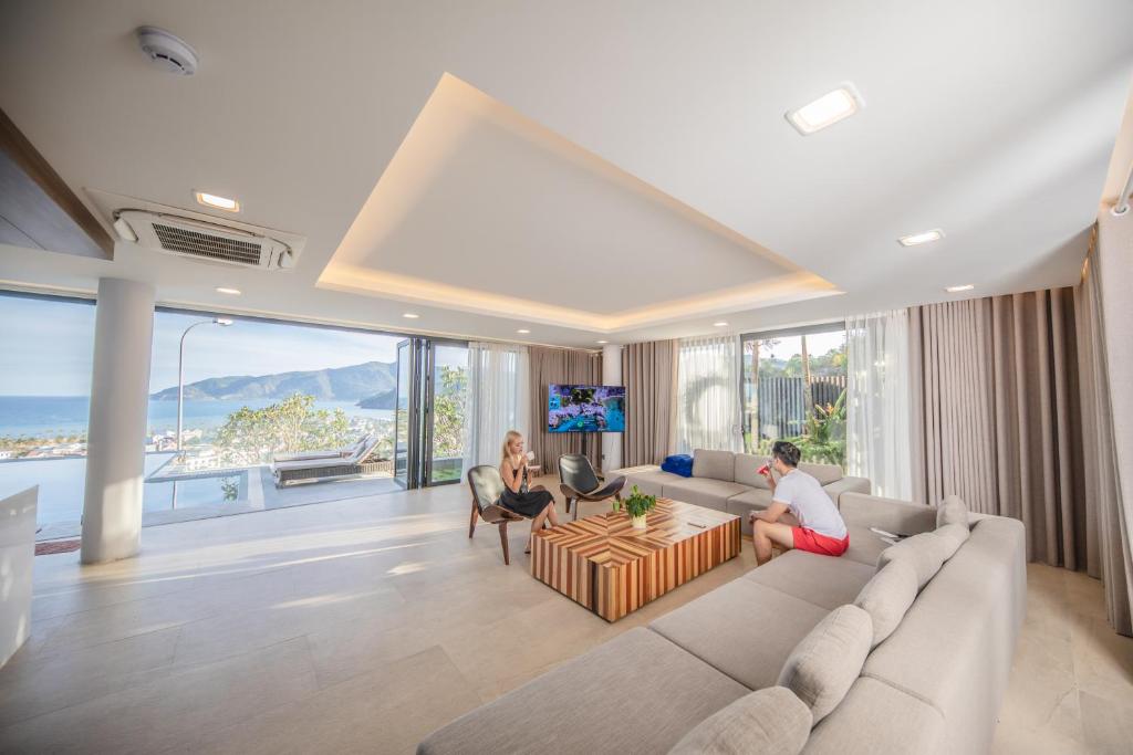 ein Wohnzimmer mit zwei Personen auf einer Couch in der Unterkunft Nha Trang Oceanfront Luxury Villa Anh Nguyen in Nha Trang