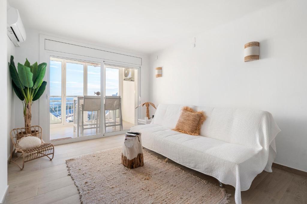 ein Wohnzimmer mit einem weißen Sofa und einem großen Fenster in der Unterkunft Apartamento WELCS EMP - 101 con vistas al Mar in Empuriabrava