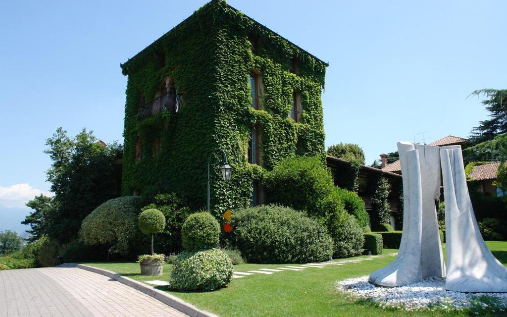 a building covered in ivy next to a garden at L'Albereta Relais & Chateaux in Erbusco