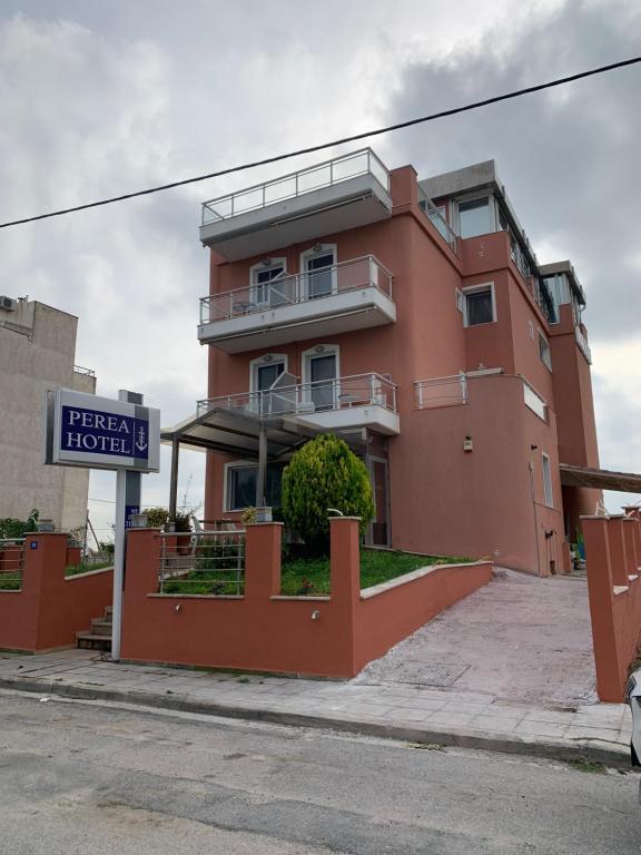 um edifício vermelho com um sinal em frente em Perea Hotel em Perea
