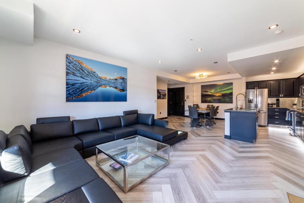 a living room with a black couch and a kitchen at #544- Luxury Village 3BR - Spa, Pool, & Walk to Gondola in Mammoth Lakes