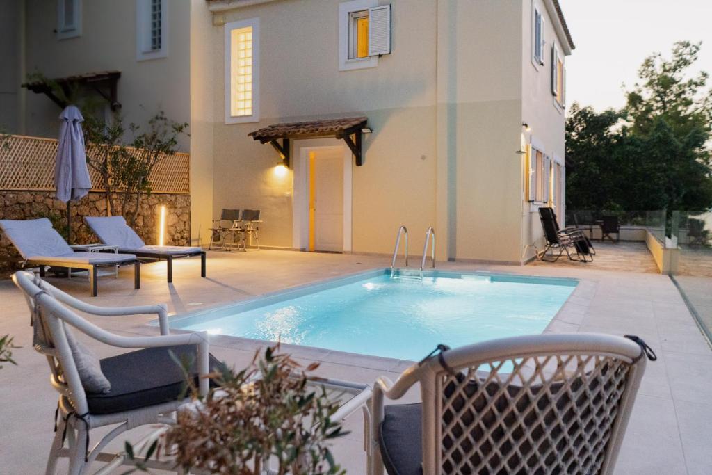 a swimming pool with chairs and a house at Iliana Exclusive Villa - Private Pool - Walking Distance To Beach in Porto Heli