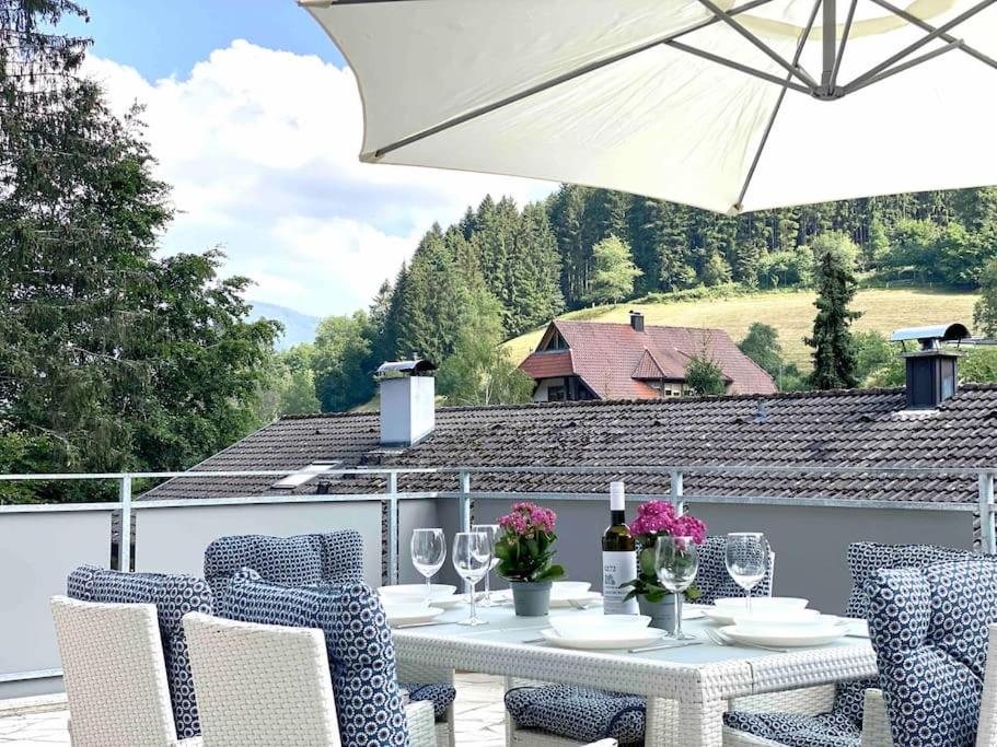 einen Tisch mit Stühlen und einem Sonnenschirm auf einer Terrasse in der Unterkunft **Schwarzwald-Haus mit Sauna** in Elzach