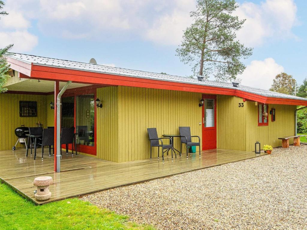 a yellow house with a red roof and a deck at 4 person holiday home in F rvang in Fårvang