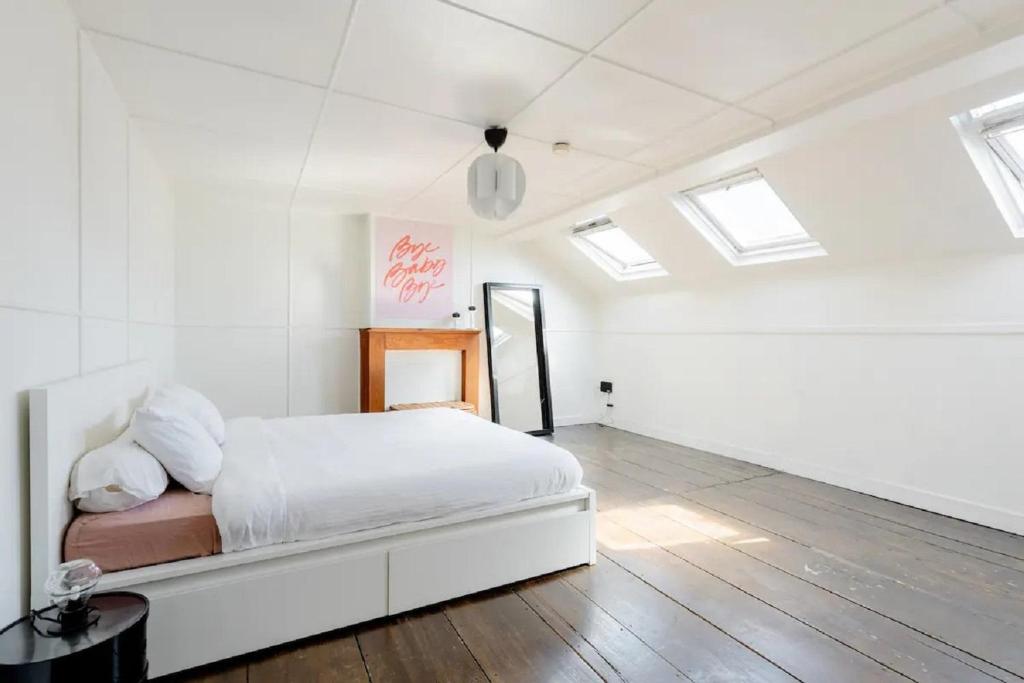 ein weißes Schlafzimmer mit einem Bett und Oberlichtern in der Unterkunft L'appartement Casquette in Lüttich
