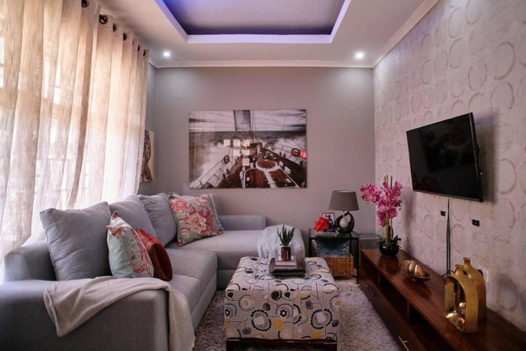 sala de estar con sofá y TV en The Hatua Peaceful Homeaway Haven en Arusha