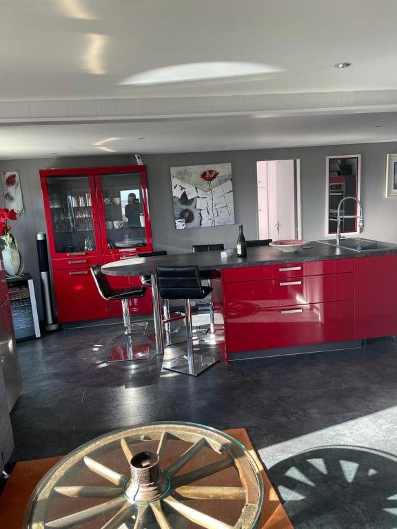 une cuisine avec des placards rouges, une table et des chaises dans l&#39;établissement Plage du Débarquement. Maison bord de Mer, à Saint-Côme-de-Fresné