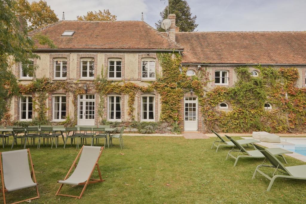 un bâtiment avec des chaises et des tables devant lui dans l'établissement Magnifique maison proche de Paris, La Prairie by Oasis House, à Égreville