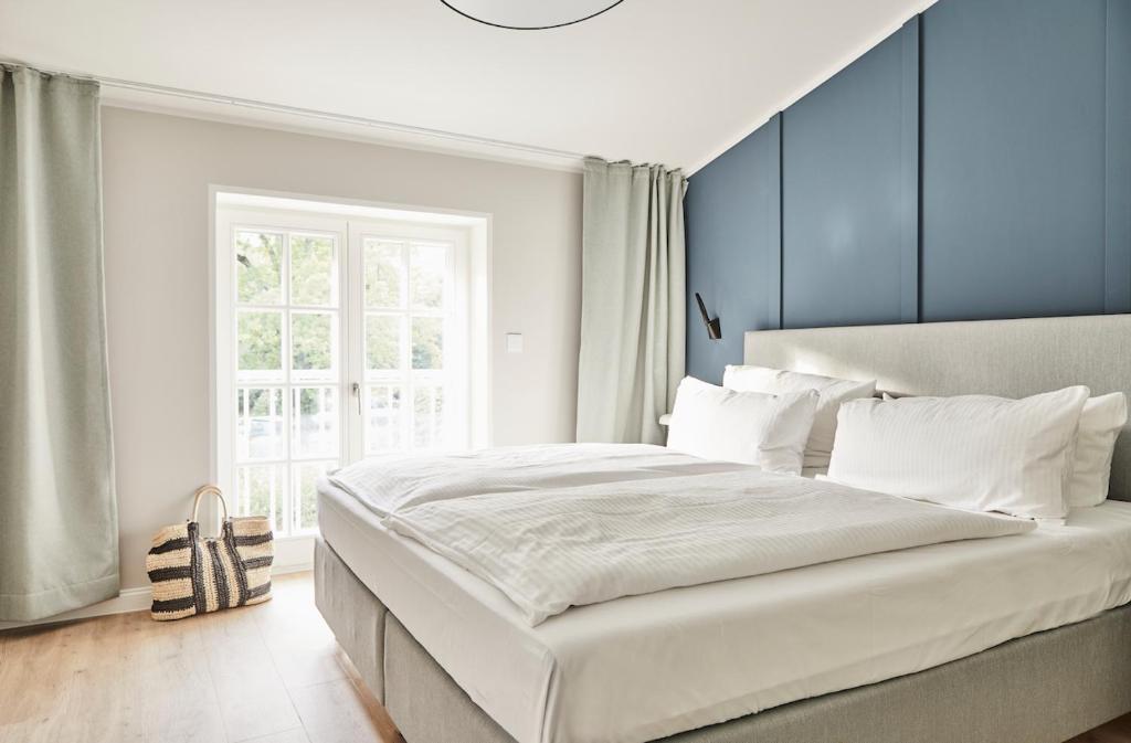 a bedroom with a large white bed with blue walls at Strandglück Prerow in Prerow