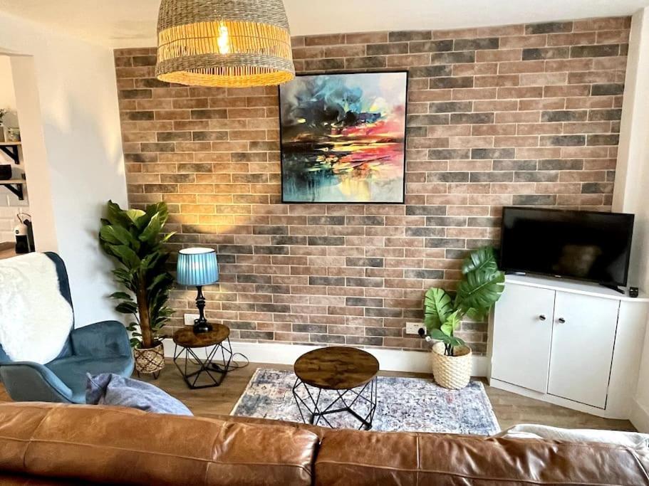 a living room with a couch and a brick wall at Terrace House - Charming home near town and train station in Nantwich