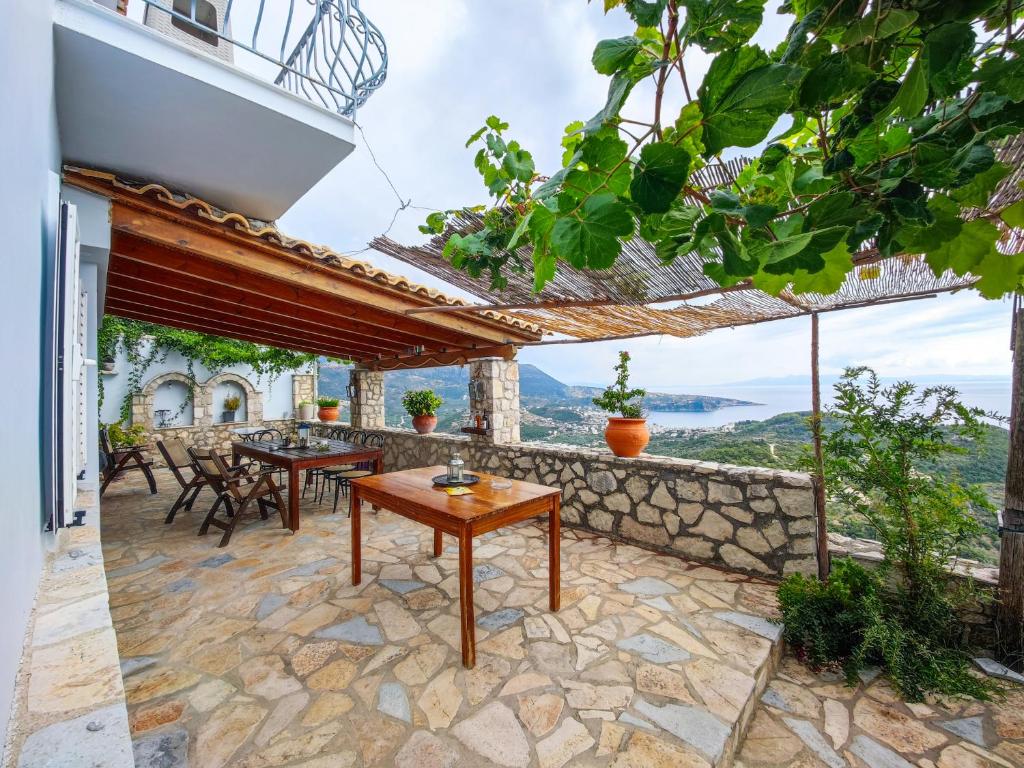 a patio with tables and chairs and a stone wall at Castle of Himara in Himare