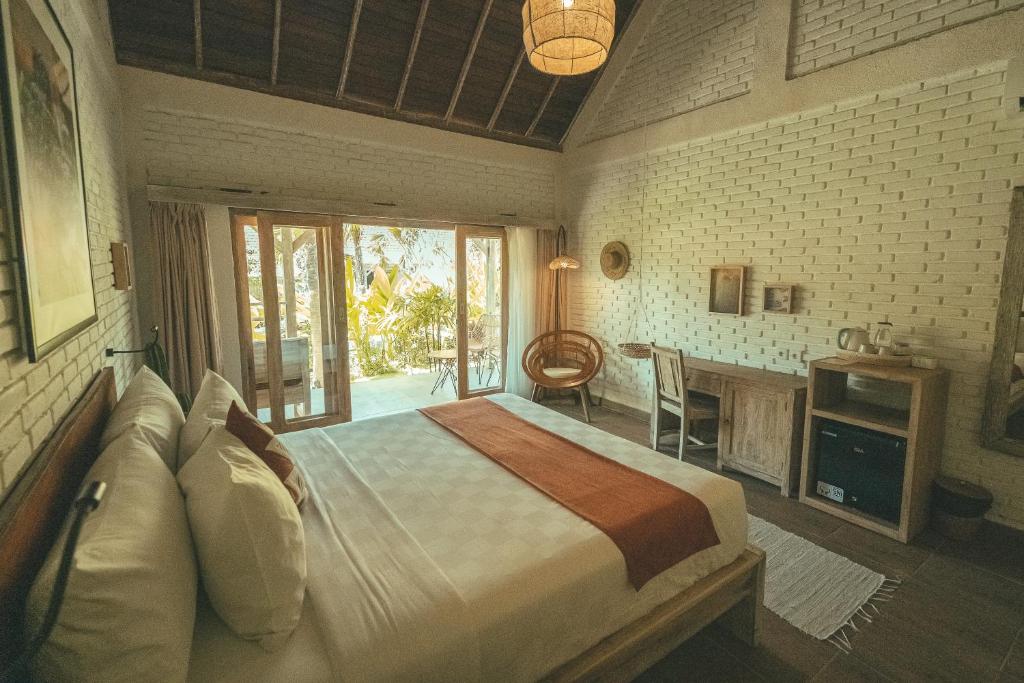 a bedroom with a bed and a desk and a table at Tamuku Padang Padang in Uluwatu