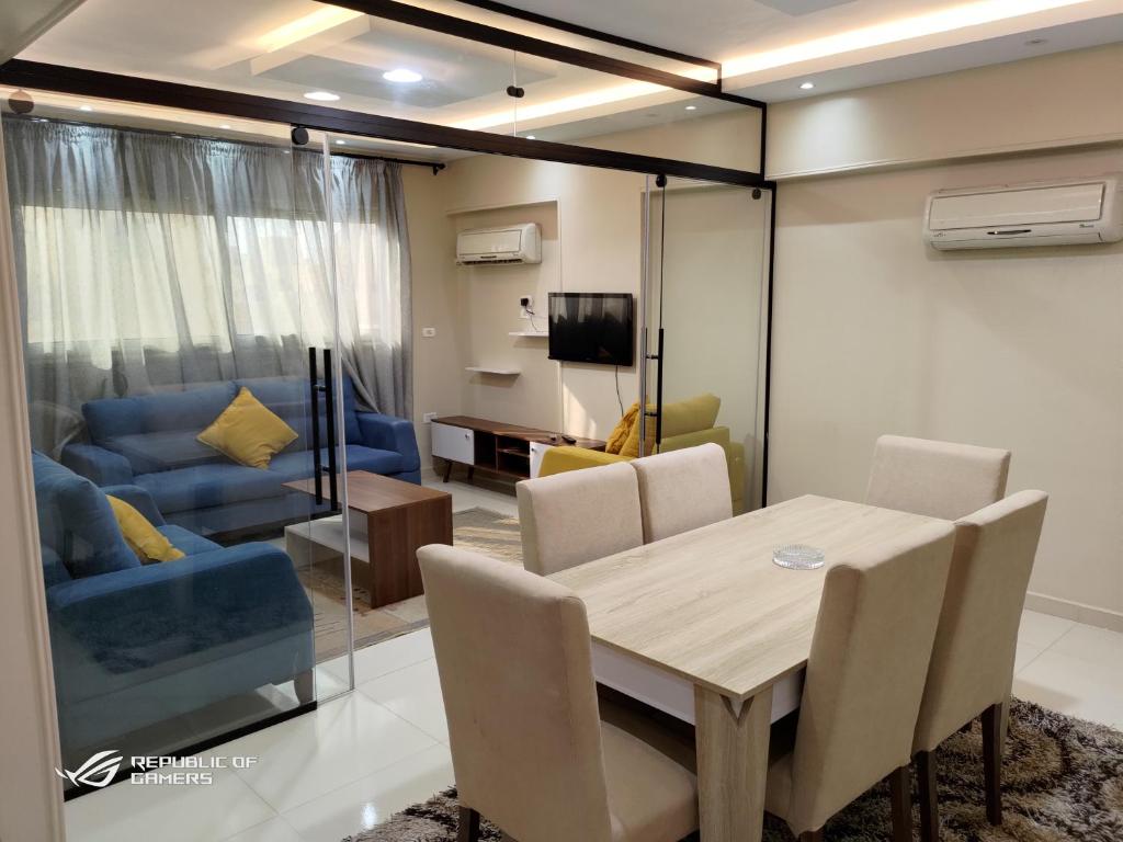 une salle à manger avec une table et un canapé bleu dans l'établissement 3 Bedrooms Luxurious Appartment in Nasr City, au Caire