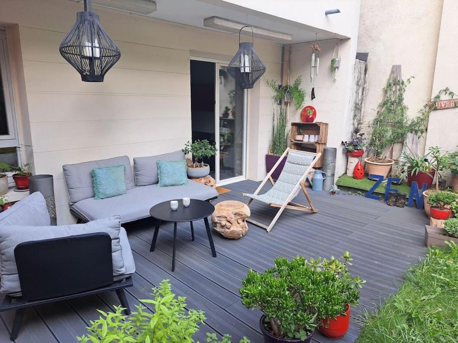 eine Terrasse mit einem Sofa und einem Tisch und einigen Pflanzen in der Unterkunft Appartement cosy avec jardin et parking in Gennevilliers