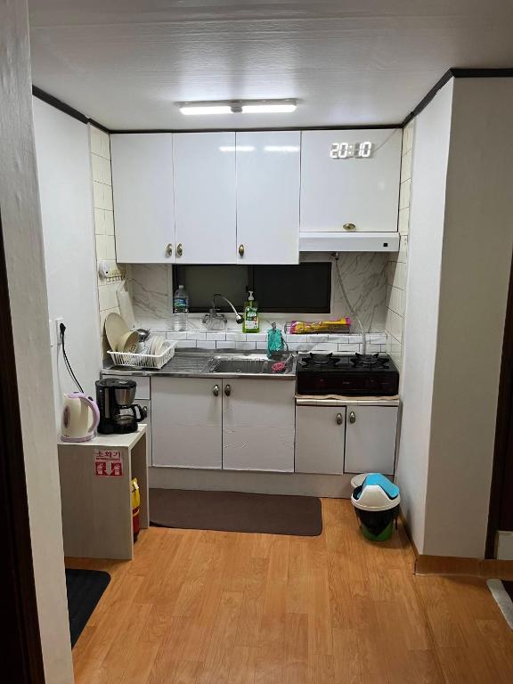 Dongming House في سول: مطبخ صغير مع دواليب بيضاء ومغسلة