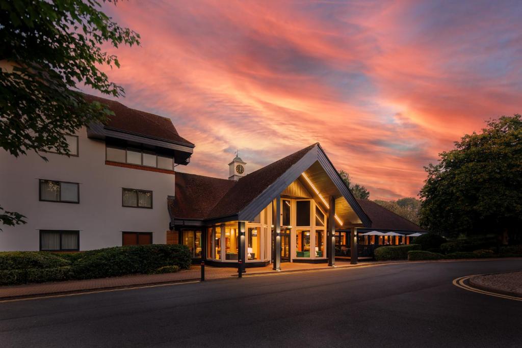 Holiday Inn Hemel Hempstead M1, Jct. 8, an IHG Hotel في هيميل هيمبستيد: مبنى مع غروب الشمس في السماء