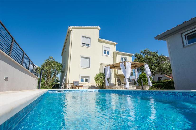 una casa con piscina frente a un edificio en Villa Ana, en Zadar