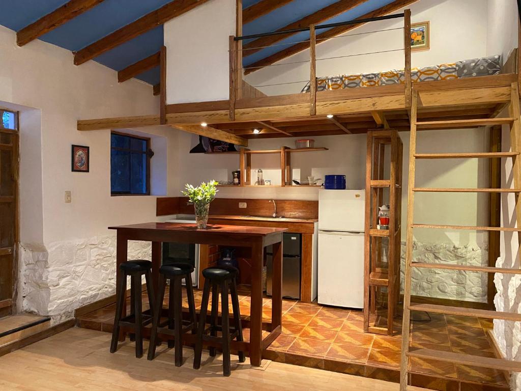 a kitchen with a loft bed and a table with stools at Casas de campo para riders in Urubamba