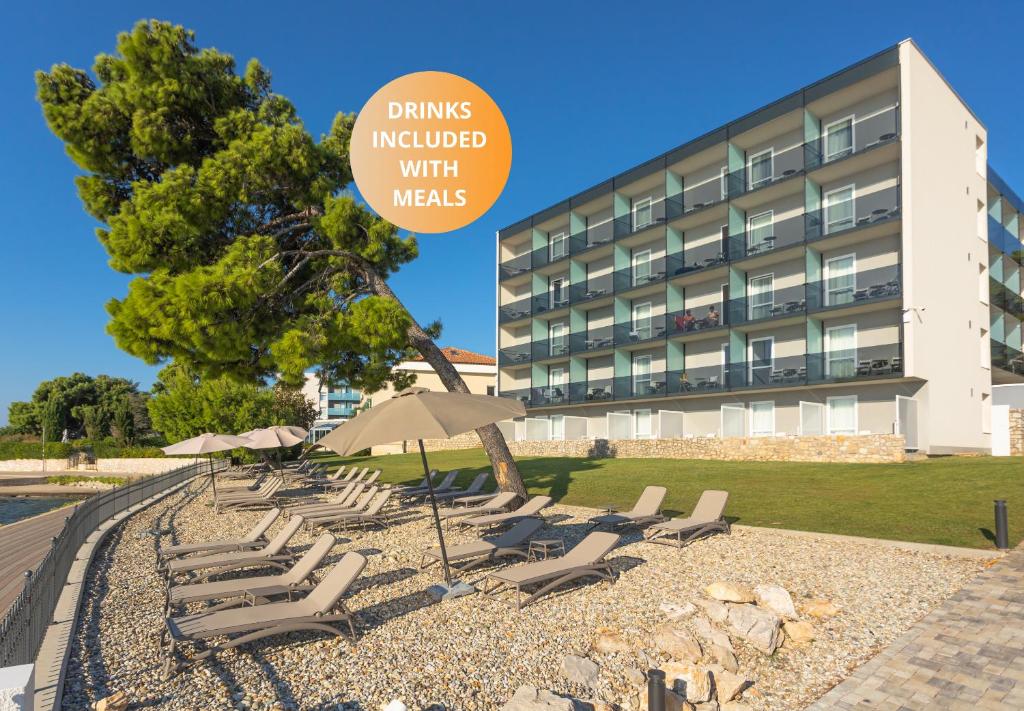 un groupe de chaises et de parasols devant un bâtiment dans l'établissement Villa Arausa, à Vodice