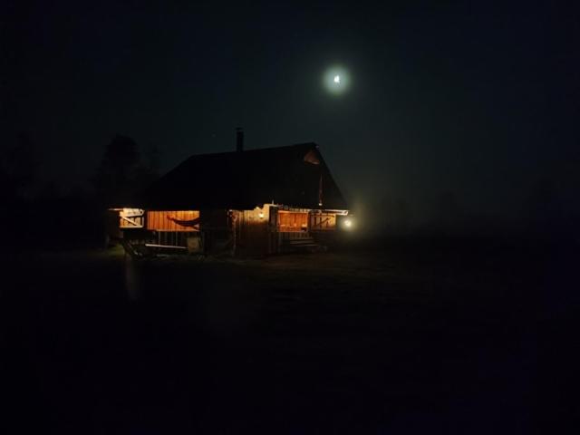 a cabin at night with the moon in the background at Sauna, balia i drewniana chata nad rzeką 