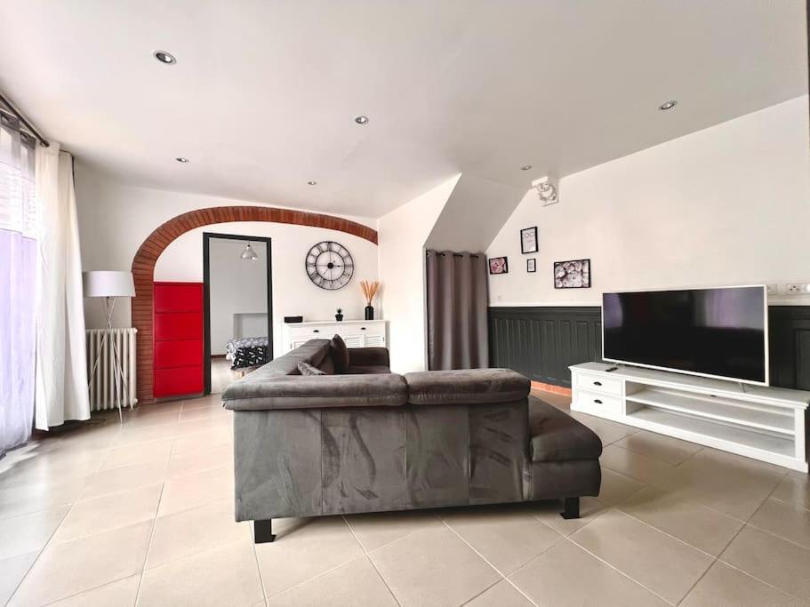 ein Wohnzimmer mit einem Sofa und einem TV in der Unterkunft Au Bord de l’Eau in Montreuil