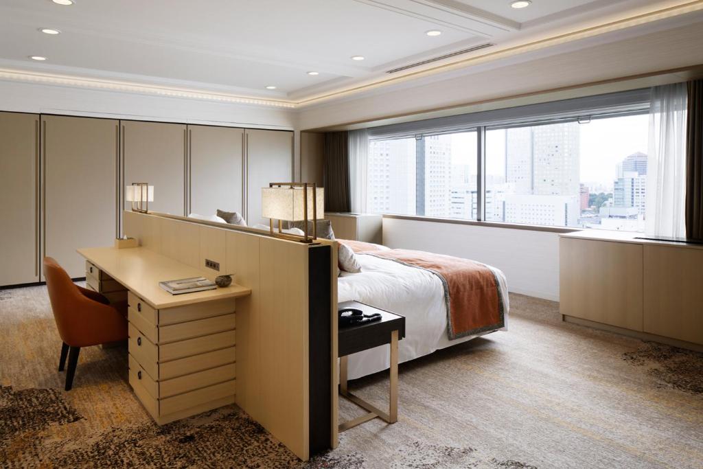 a hotel room with a bed and a desk and a window at Grand Prince Hotel Takanawa in Tokyo