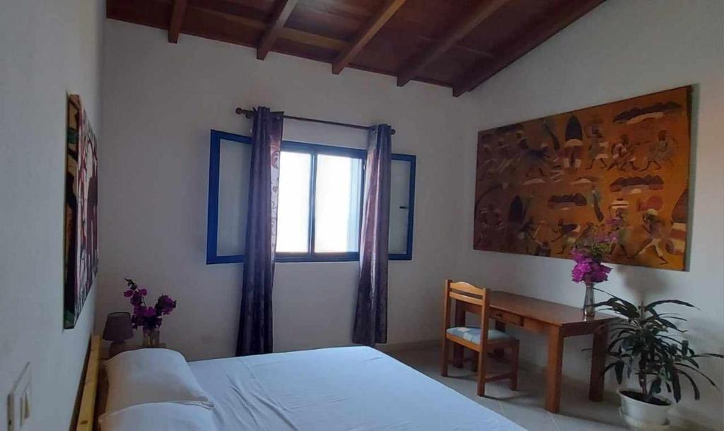 a bedroom with a bed and a table and a window at Casa Torre in Palmeira