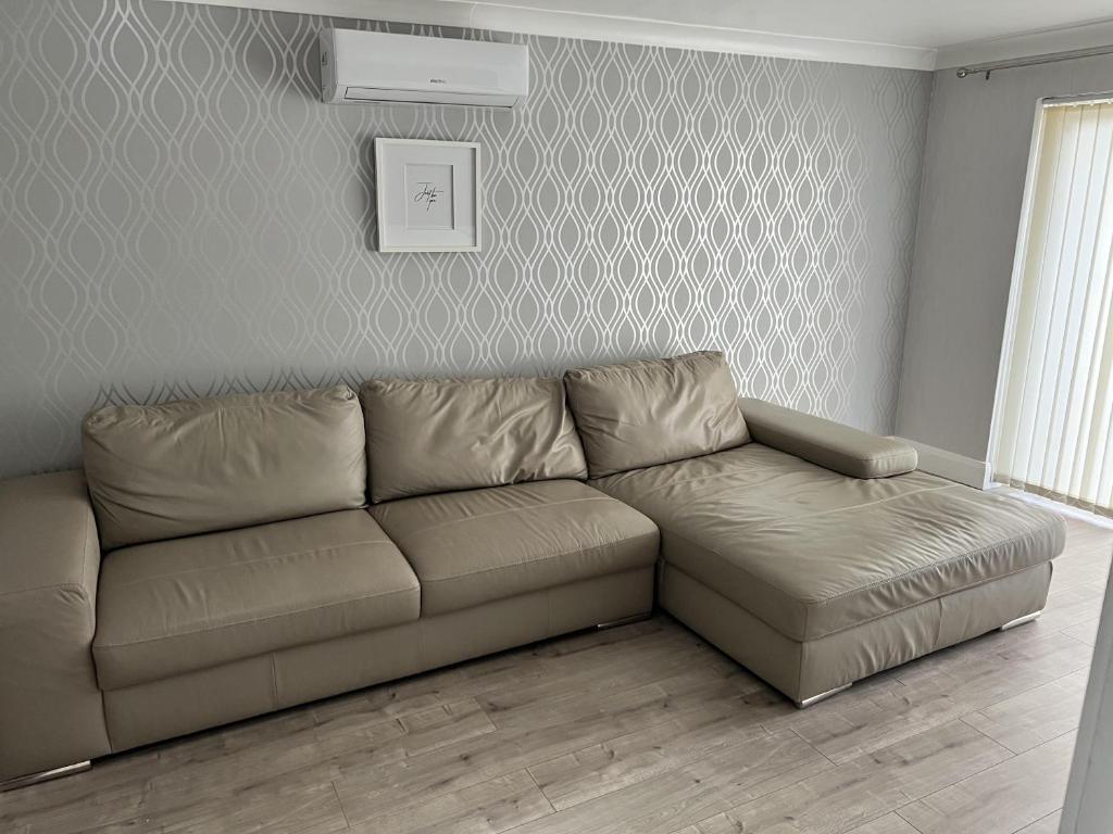ein braunes Sofa in einem Wohnzimmer mit einer Wand in der Unterkunft Remarkable 3-Bed House in Basildon in Basildon