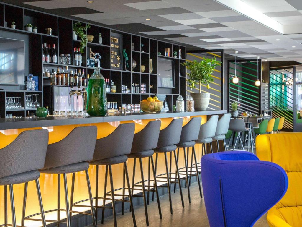 un bar con sillas amarillas y azules en un restaurante en Mercure Hyères Centre Côte d'Azur, en Hyères