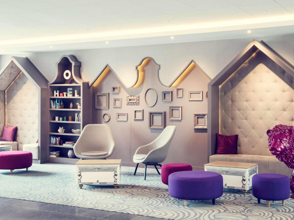 een woonkamer met paarse stoelen en een bank bij Mercure Gdańsk Posejdon in Gdańsk