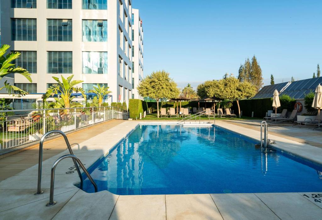 a large blue swimming pool in front of a building at Hilton Garden Inn Sevilla in Seville