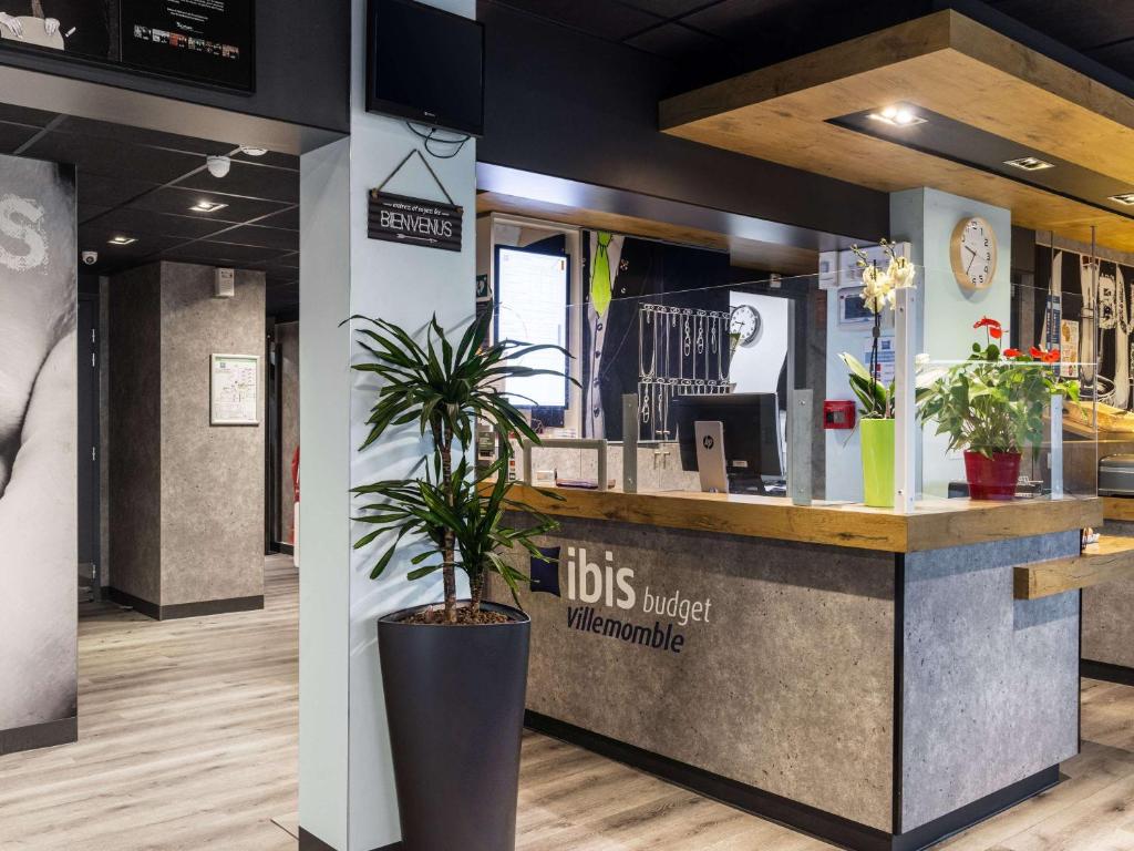 a restaurant with a counter with a potted plant at ibis Budget Villemomble in Villemomble