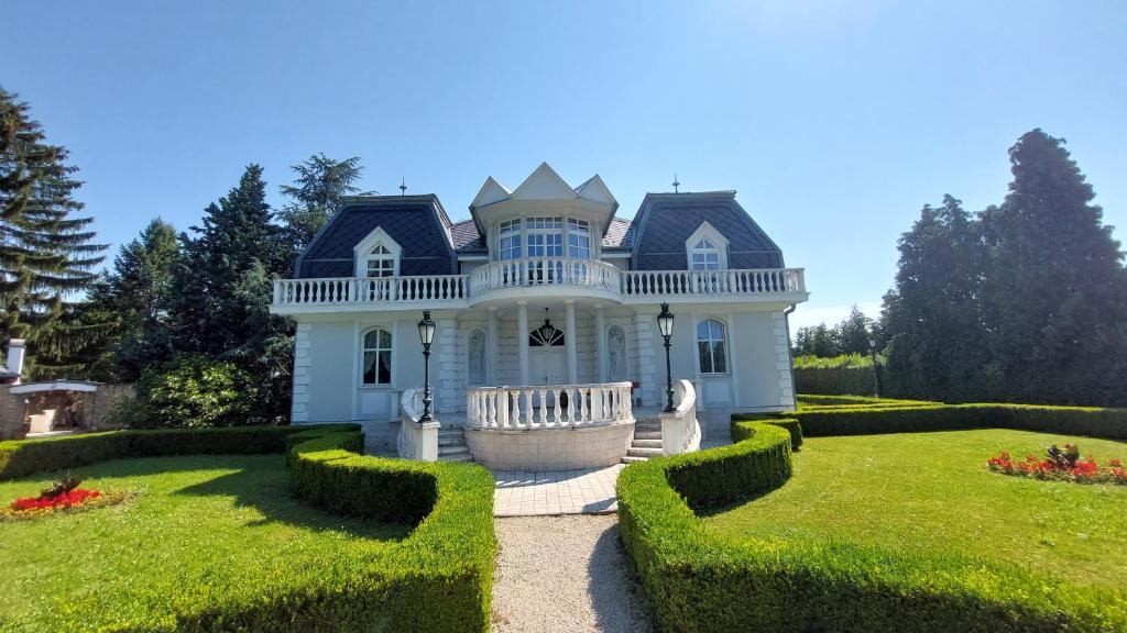 une grande maison blanche avec une grande cour dans l'établissement Castle Garden ***, à Szombathely