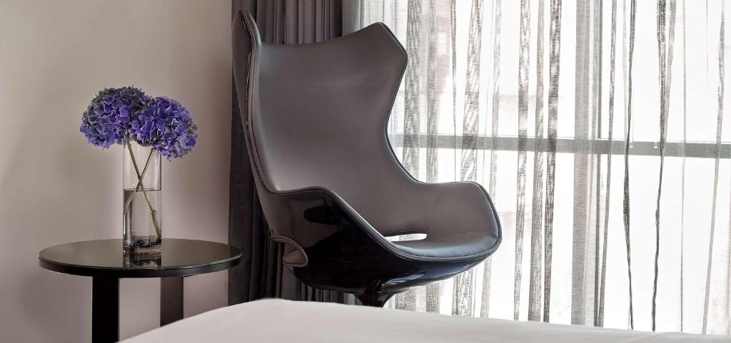 a black chair next to a table with a vase of purple flowers at Park Plaza London Riverbank in London