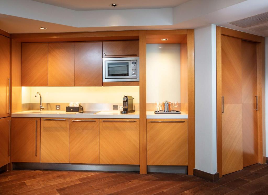a kitchen with wooden cabinets and a microwave at Park Plaza London Riverbank in London