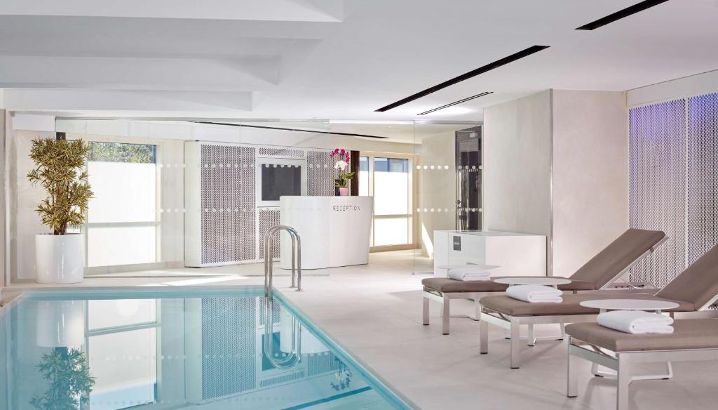 a bathroom with a swimming pool and chairs at Park Plaza London Riverbank in London