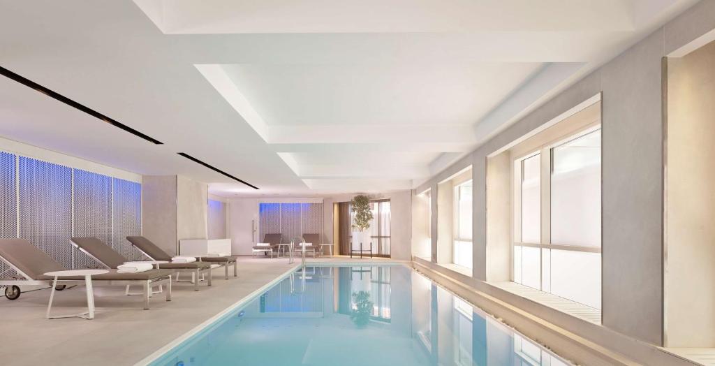 a swimming pool with chairs and a table in a building at Park Plaza London Riverbank in London