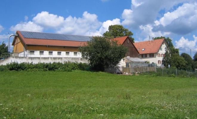 a large building with a grass field in front of it at Ferienhof Roller in Simmersfeld