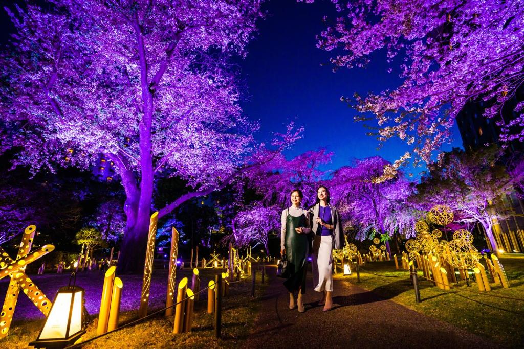 two women walking through a cemetery at night with purple trees at Grand Prince Hotel Shin Takanawa in Tokyo