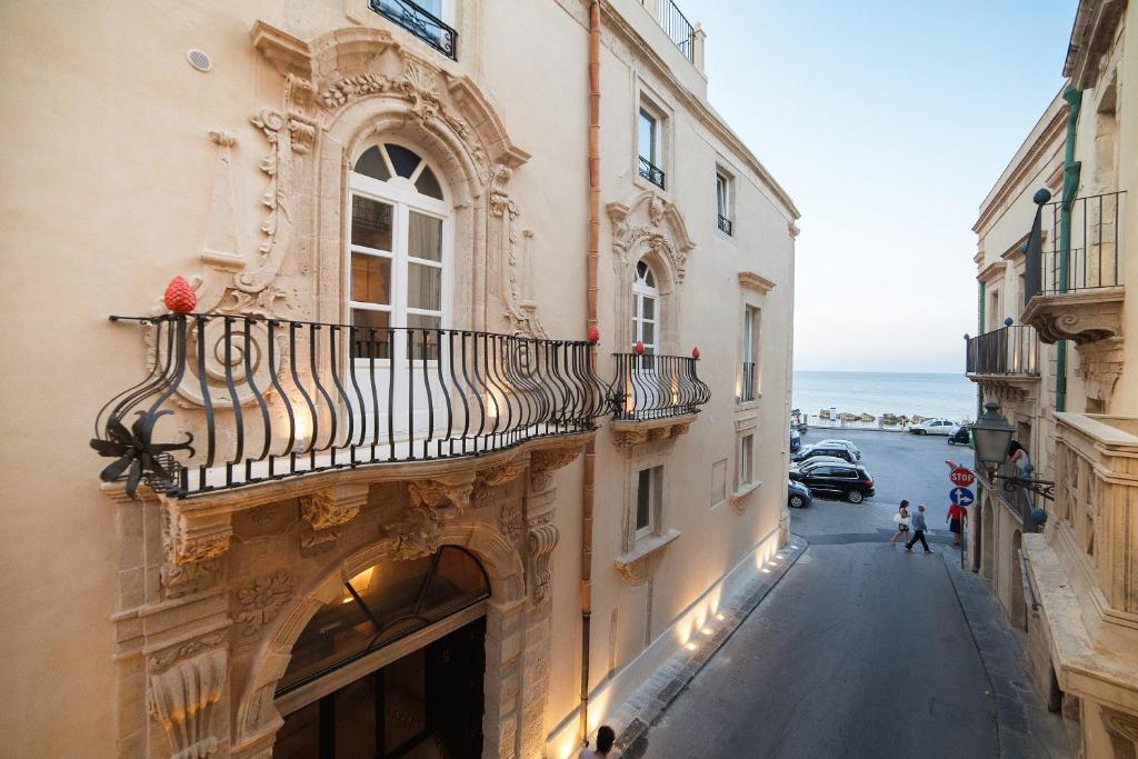 an old building with a balcony on a street at Algilà Ortigia Charme Hotel in Siracusa