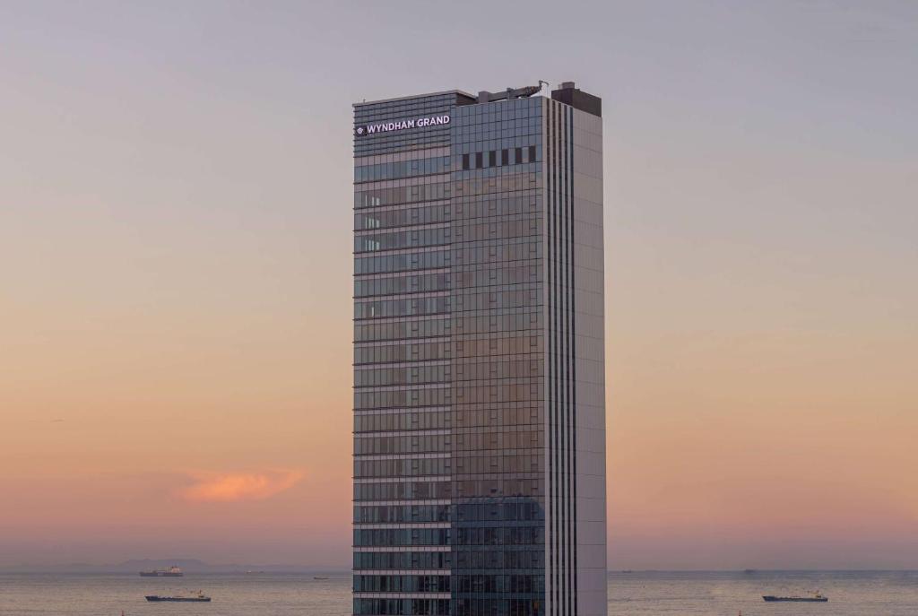 a tall building on the ocean with a sunset at Wyndham Grand Busan in Busan