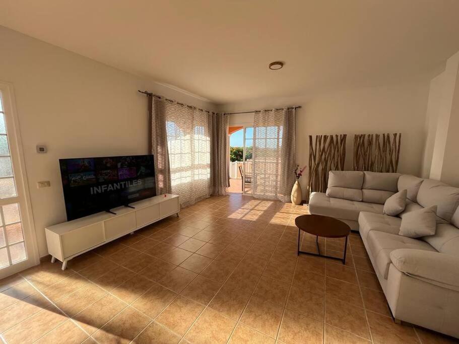 a living room with a couch and a flat screen tv at Chalet piscina privada max 26º Jardín, tranquilidad in Garachico