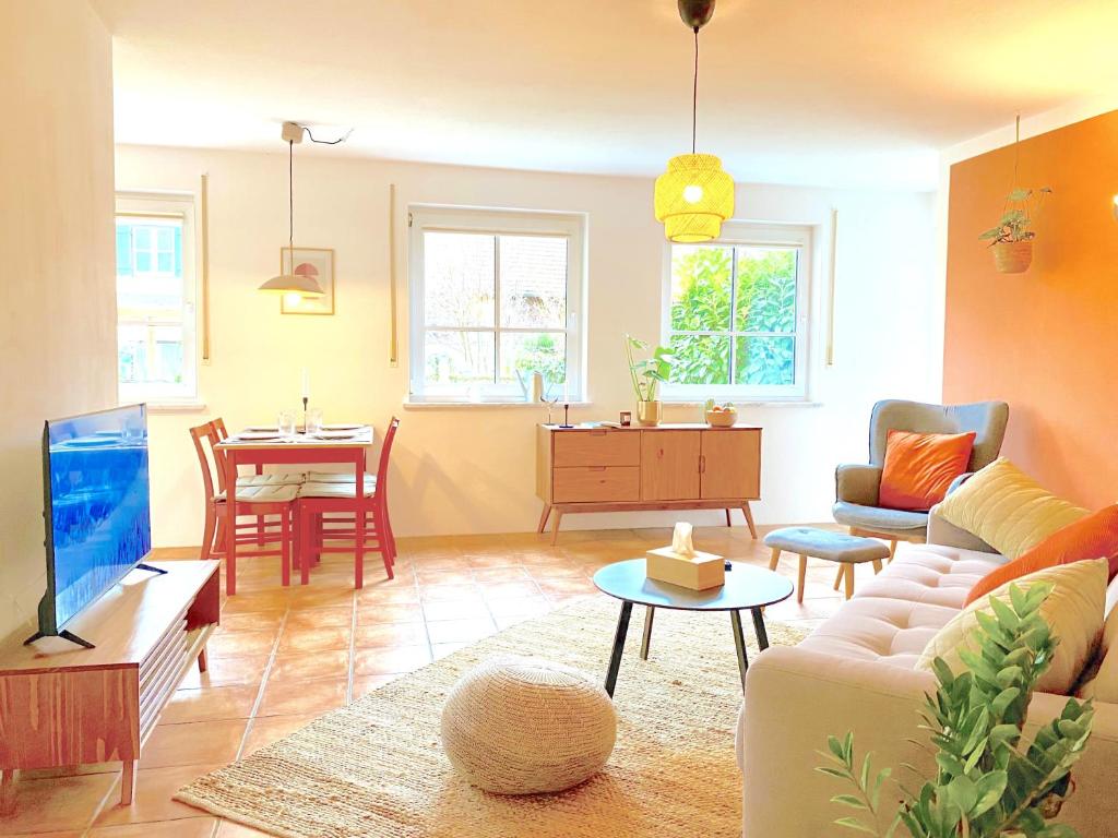 een woonkamer met een bank en een tafel bij Snug Stays I 3 Zimmer Design Apartment am See mit Garten I Home Office I Highspeed Wifi in Weßling
