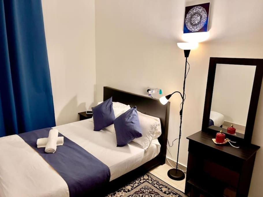 ein Schlafzimmer mit einem Bett mit einem Spiegel und einer Lampe in der Unterkunft Dilla Homestay At Bangi UKM Kajang in Kajang
