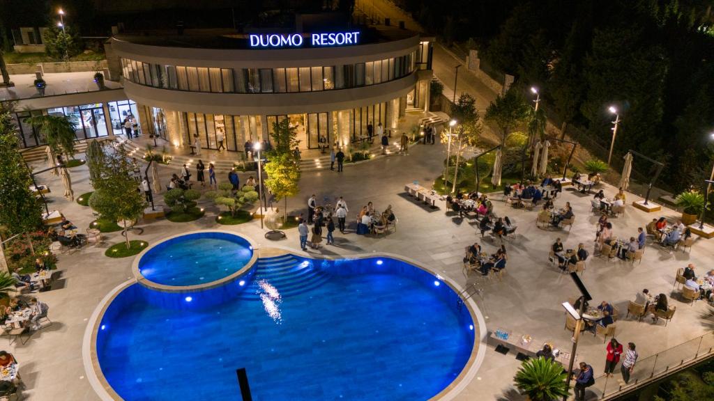 an overhead view of a large blue pool in front of a building at Duomo Resort in Shkodër