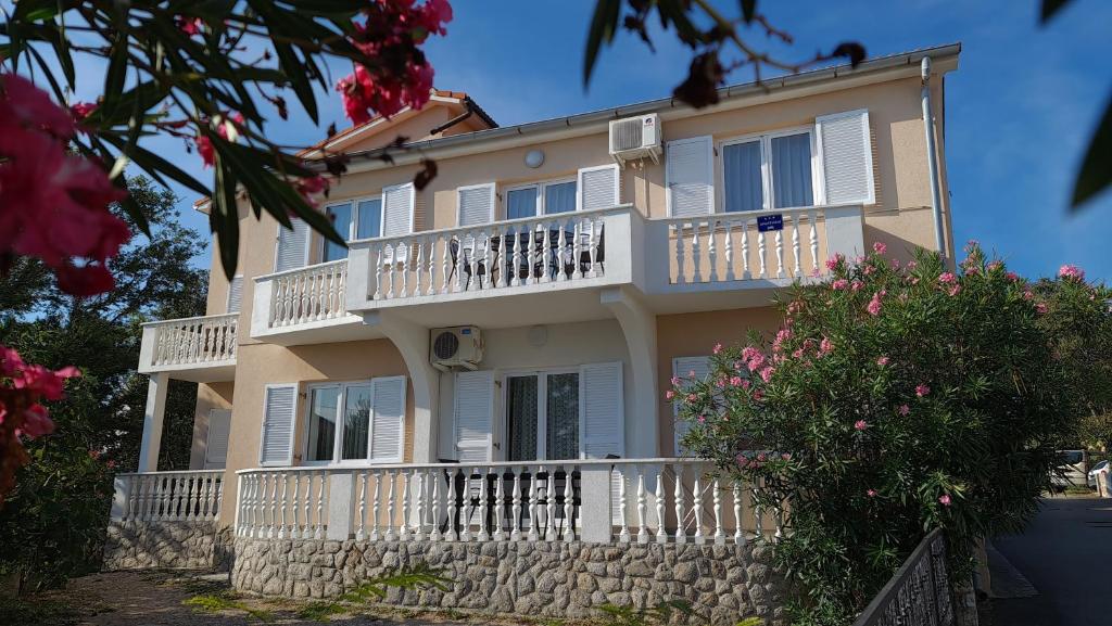 a large house with balconies and a stone wall at Apartments Mihalic in Šilo