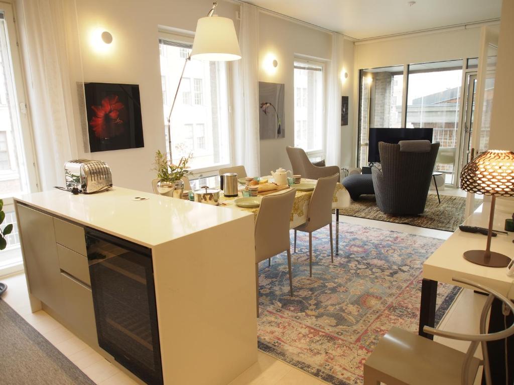 Luxury City Seafront Apartment with Balcony في هلسنكي: مطبخ وغرفة معيشة مع طاولة وكراسي