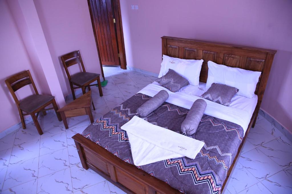 a bedroom with a large bed with two chairs at MICASA Hotel in Mbarara