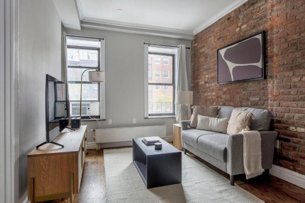 uma sala de estar com um sofá e uma parede de tijolos em East Village 2br w wd nr union square NYC-1260 em Nova York